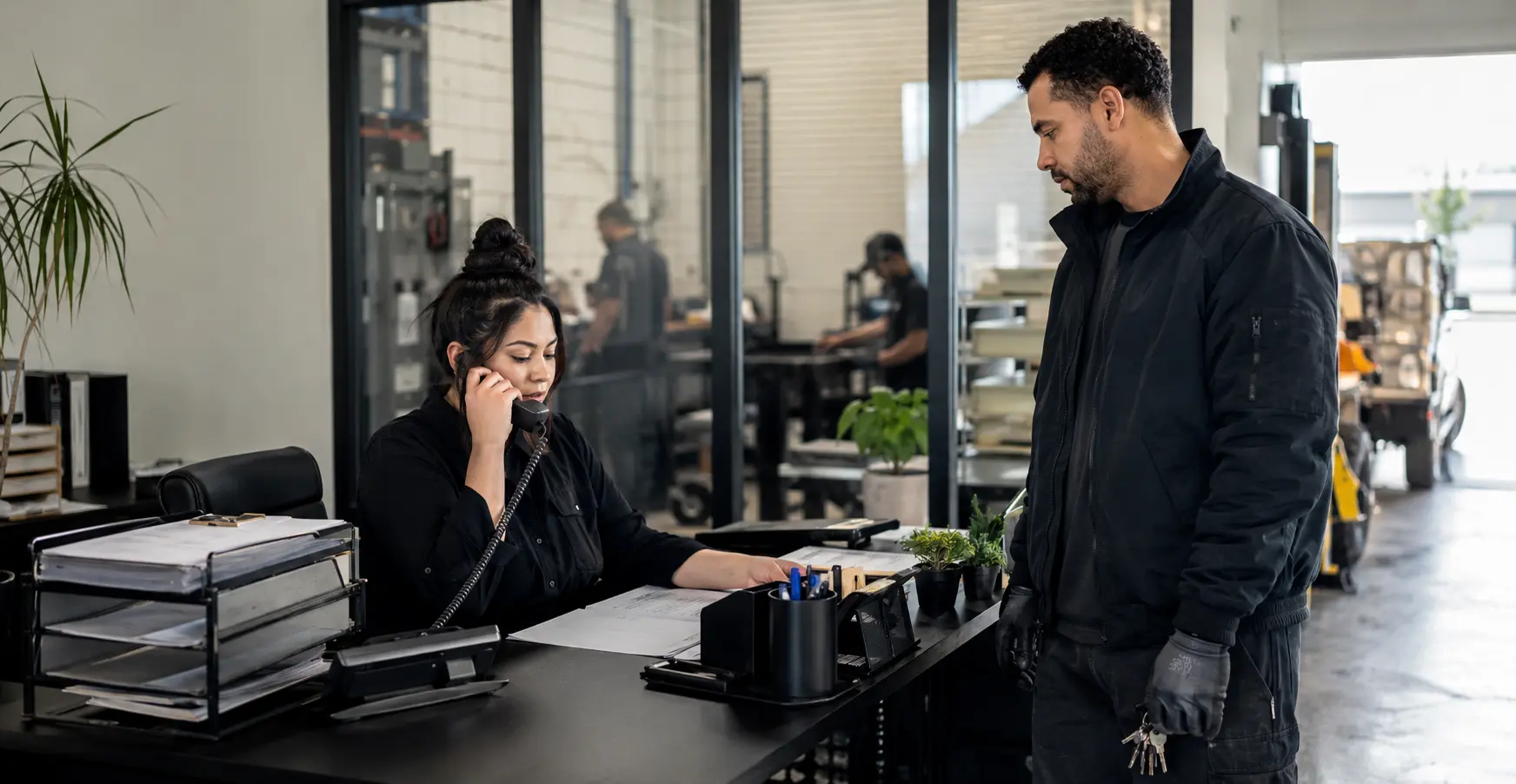 A receptionist handling a call while a colleague works at the front desk